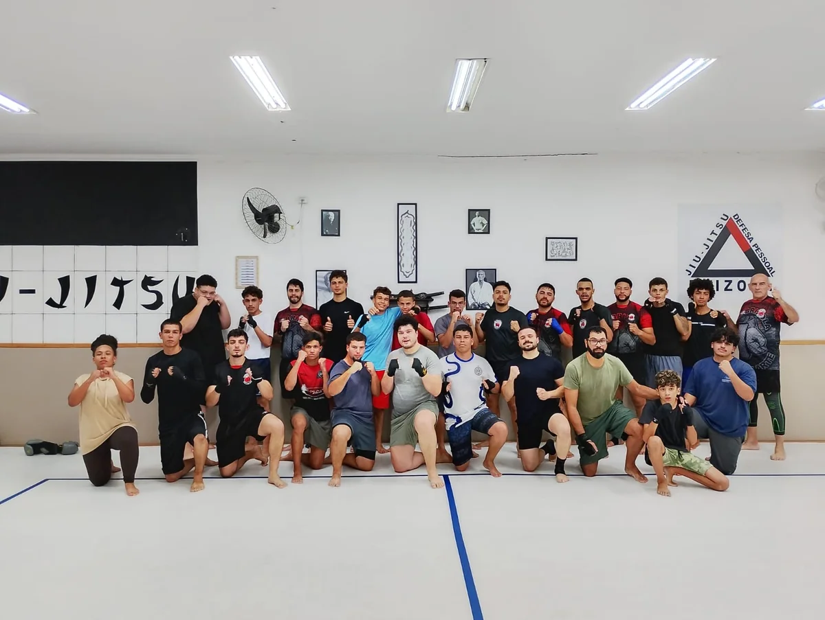 Turma reunida no tatame, com o símbolo da Brizola na parede